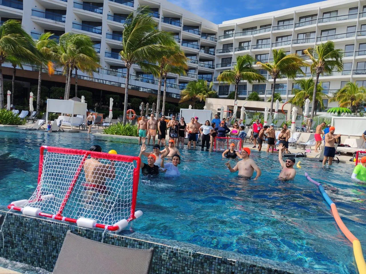 Participantes en reto de waterpolo corporativo en la alberca de un hotel de Cancún